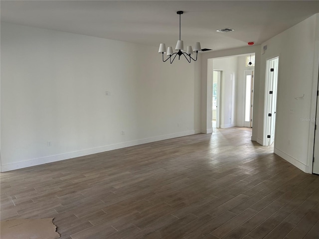 spare room with dark hardwood / wood-style flooring and a chandelier