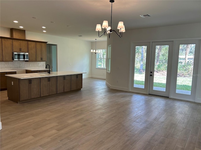 kitchen featuring decorative light fixtures, sink, a center island with sink, and a notable chandelier