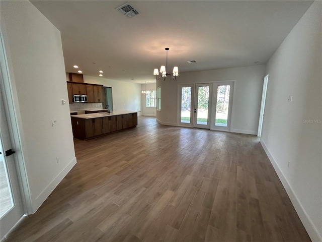 unfurnished living room featuring hardwood / wood-style flooring, sink, and a notable chandelier