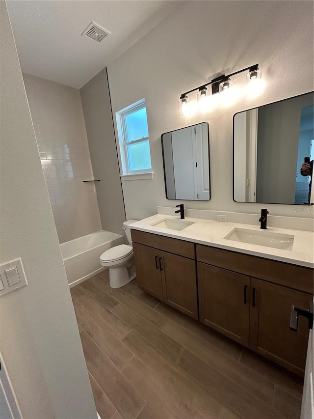 full bathroom with vanity, tub / shower combination, hardwood / wood-style floors, and toilet