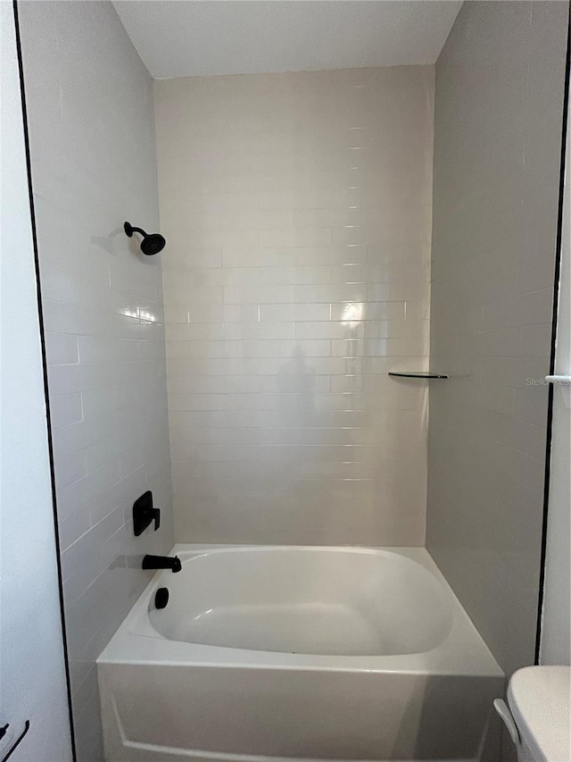 bathroom featuring toilet and tiled shower / bath