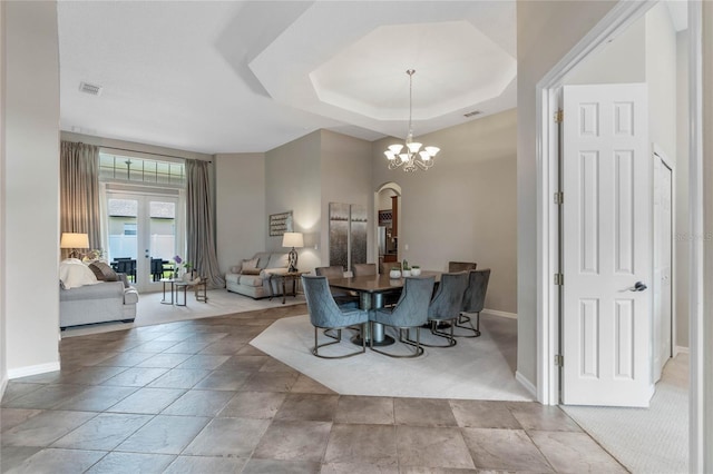 carpeted dining room with a raised ceiling and an inviting chandelier