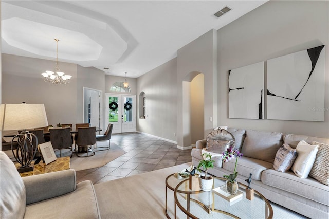 tiled living room featuring a tray ceiling and a chandelier