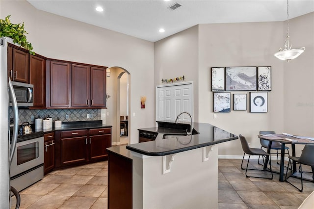 kitchen with decorative backsplash, stainless steel appliances, sink, a center island with sink, and a breakfast bar area