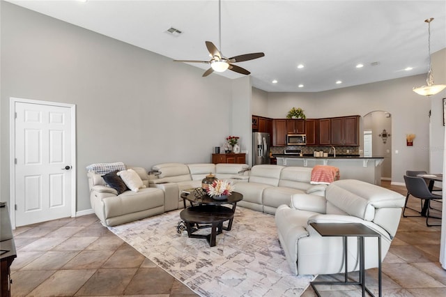 living room with a towering ceiling and ceiling fan