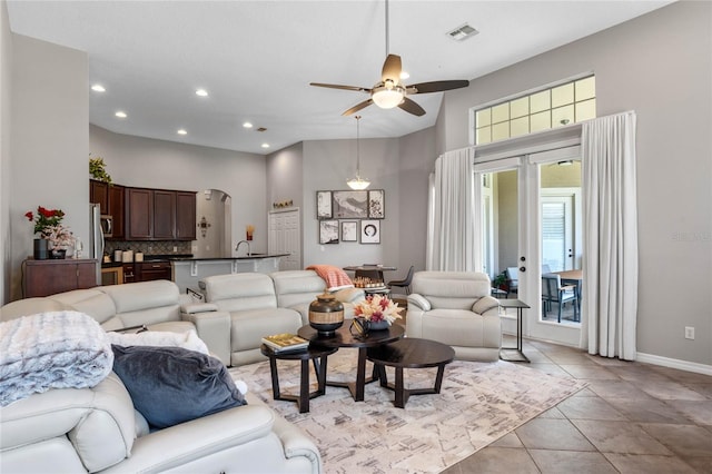 tiled living room featuring ceiling fan and a high ceiling