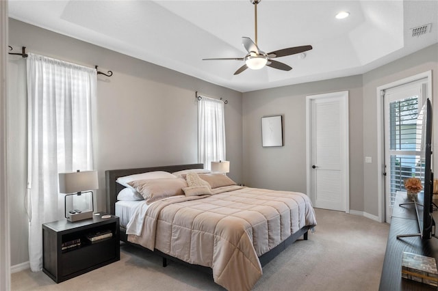 carpeted bedroom with ceiling fan, a raised ceiling, and access to outside