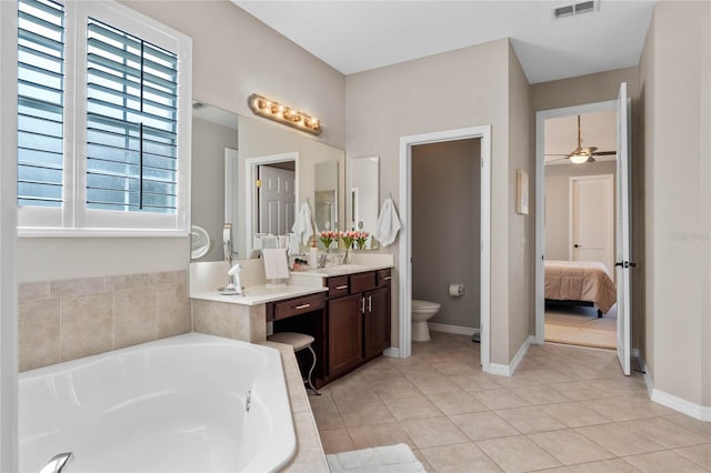 bathroom with vanity, tile patterned floors, ceiling fan, toilet, and tiled tub