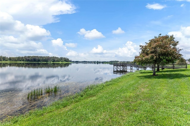 dock area with a lawn and a water view