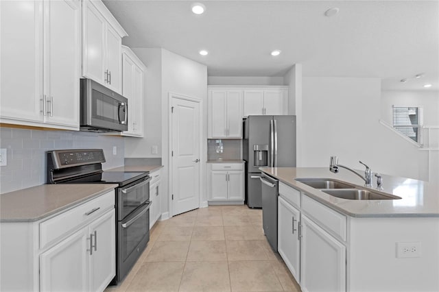 kitchen with an island with sink, stainless steel appliances, white cabinets, and sink