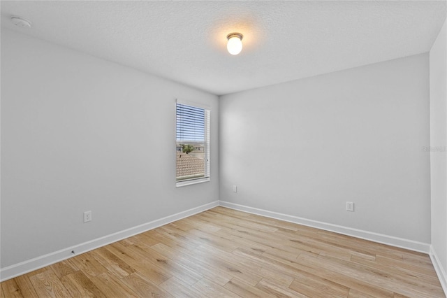 unfurnished room featuring a textured ceiling and light hardwood / wood-style flooring