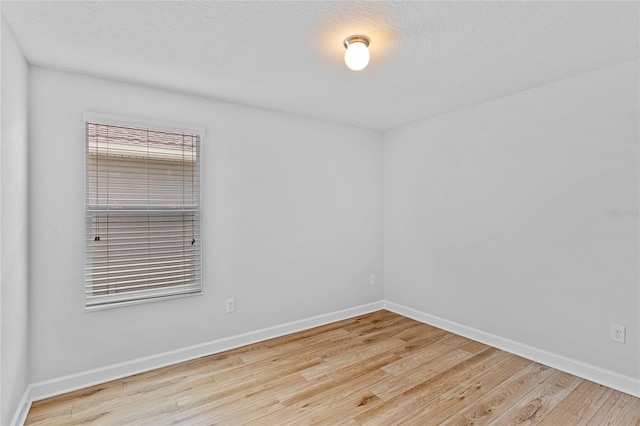 unfurnished room featuring light wood-type flooring and a textured ceiling