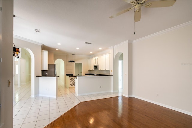 kitchen featuring kitchen peninsula, white cabinets, hanging light fixtures, appliances with stainless steel finishes, and light hardwood / wood-style floors