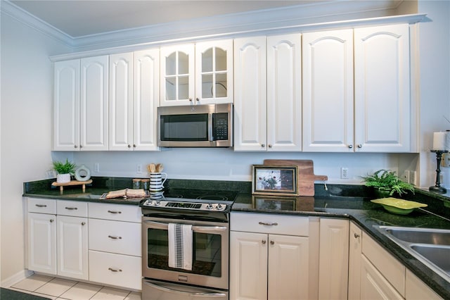 kitchen featuring appliances with stainless steel finishes, white cabinetry, ornamental molding, light tile patterned flooring, and sink