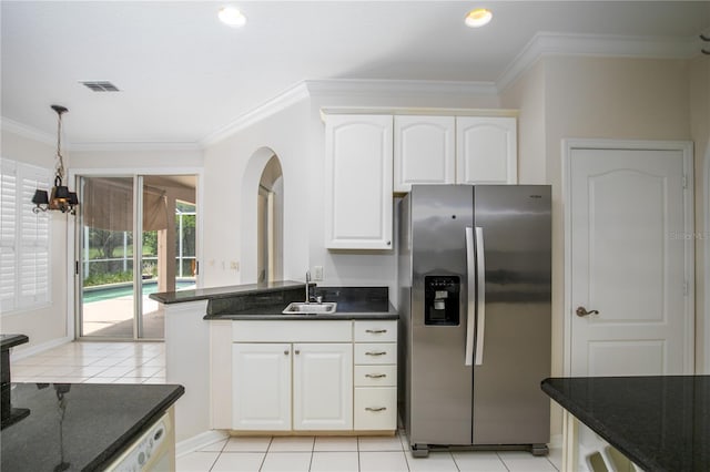 kitchen with stainless steel fridge, white cabinets, dark stone countertops, a notable chandelier, and sink