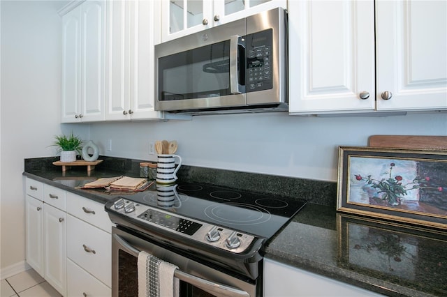 kitchen with appliances with stainless steel finishes, white cabinets, dark stone counters, and light tile patterned floors