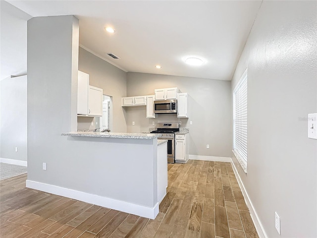 kitchen featuring appliances with stainless steel finishes, lofted ceiling, light hardwood / wood-style floors, and white cabinets