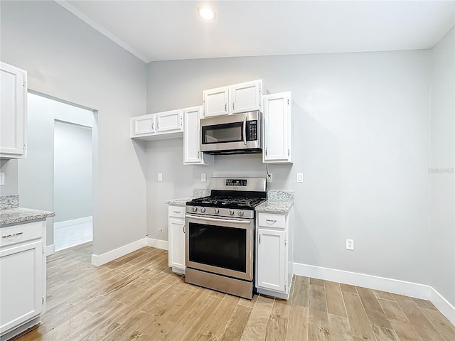 kitchen with white cabinets, appliances with stainless steel finishes, vaulted ceiling, and light hardwood / wood-style flooring