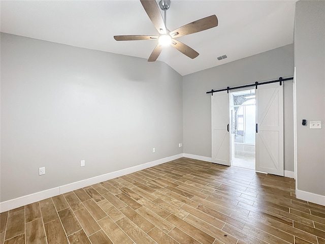 unfurnished room with a barn door, wood-type flooring, lofted ceiling, and ceiling fan