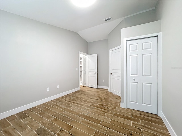 unfurnished bedroom featuring vaulted ceiling, a closet, and dark hardwood / wood-style flooring