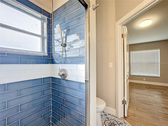 bathroom with a tile shower, hardwood / wood-style flooring, and toilet