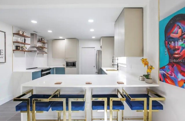 kitchen with kitchen peninsula, gray cabinetry, ventilation hood, stainless steel appliances, and a breakfast bar