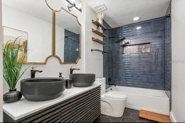 full bathroom with vanity, a textured ceiling, tile patterned flooring, toilet, and tiled shower / bath