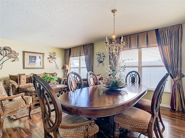 dining space with a notable chandelier, a textured ceiling, and dark hardwood / wood-style flooring