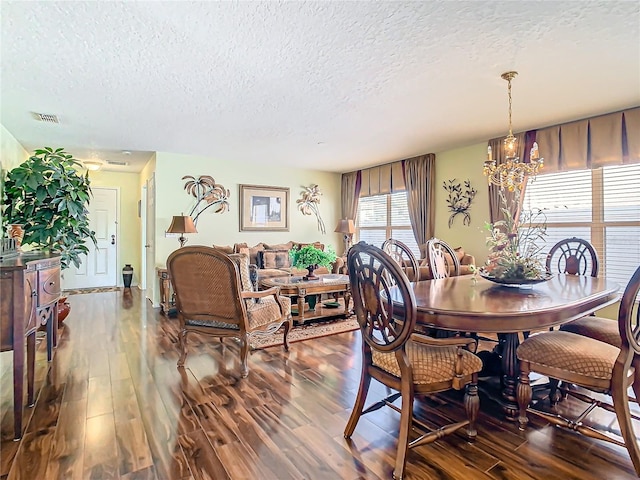 dining room featuring a notable chandelier, a textured ceiling, and dark hardwood / wood-style flooring