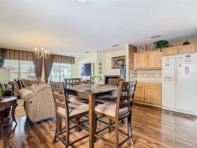 dining room featuring an inviting chandelier, dark wood-type flooring, and a textured ceiling