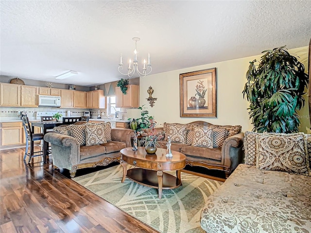 living room with a textured ceiling, an inviting chandelier, light hardwood / wood-style flooring, and sink