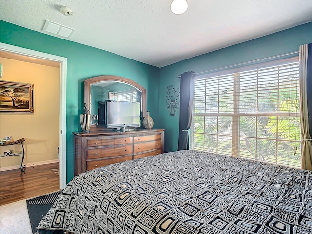 bedroom with a textured ceiling and wood-type flooring