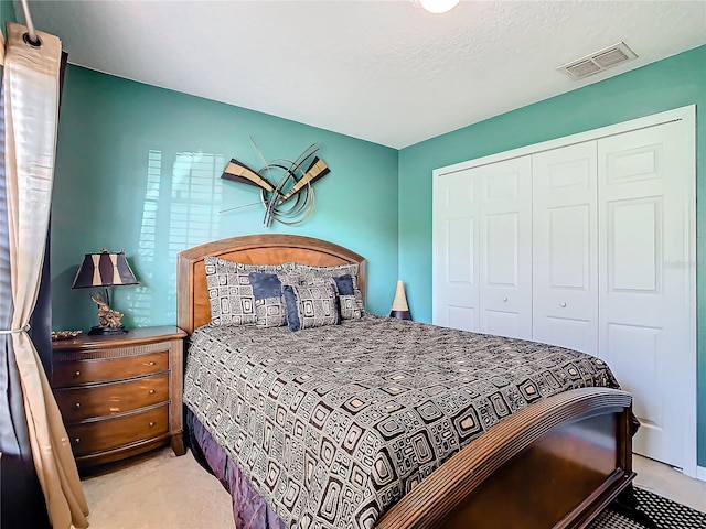 bedroom with a closet, light colored carpet, and a textured ceiling