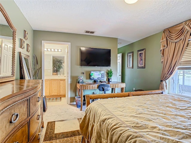 carpeted bedroom featuring a textured ceiling and ensuite bathroom