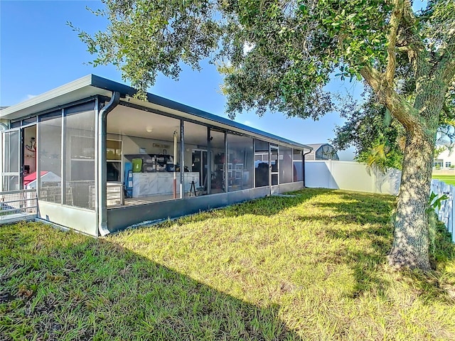 back of property with a sunroom and a lawn