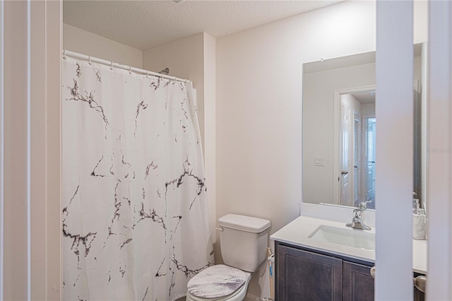 bathroom with a textured ceiling, curtained shower, vanity, and toilet