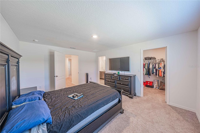 carpeted bedroom with a closet, a walk in closet, and a textured ceiling