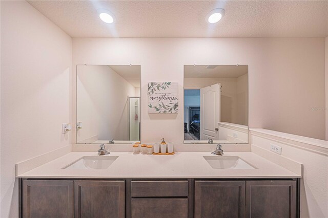 bathroom with a textured ceiling, vanity, and walk in shower