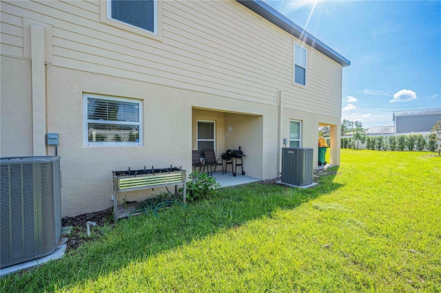 rear view of property with a lawn, a patio, and central AC