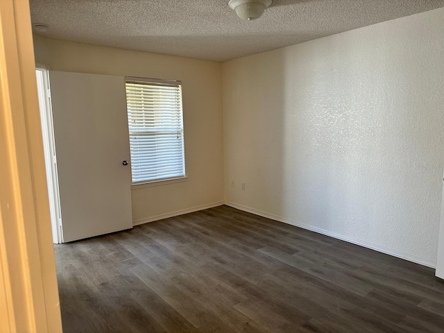 unfurnished room featuring dark hardwood / wood-style flooring and a textured ceiling