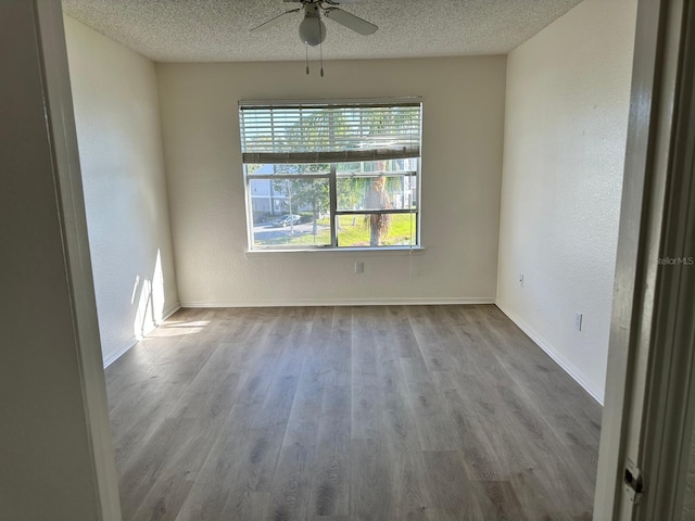 unfurnished room with ceiling fan, a textured ceiling, and light hardwood / wood-style flooring