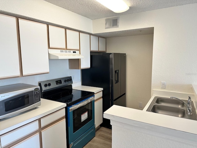 kitchen with white cabinets, sink, light hardwood / wood-style flooring, a textured ceiling, and stainless steel appliances