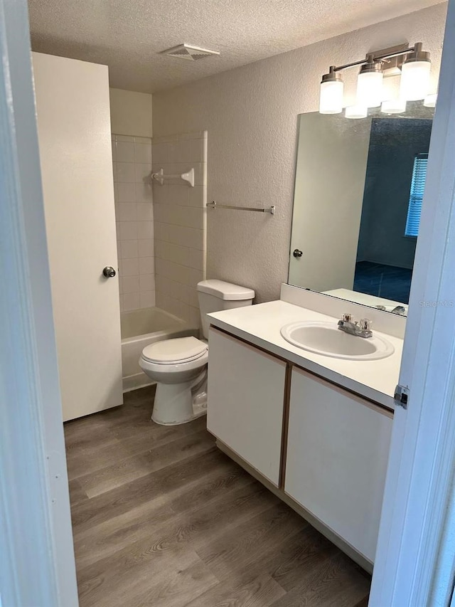 full bathroom featuring a textured ceiling, toilet, vanity, bathtub / shower combination, and hardwood / wood-style flooring