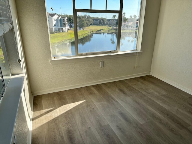 unfurnished room featuring hardwood / wood-style floors and a water view