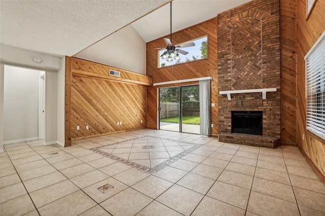 unfurnished living room with high vaulted ceiling, wooden walls, a textured ceiling, and light tile patterned flooring