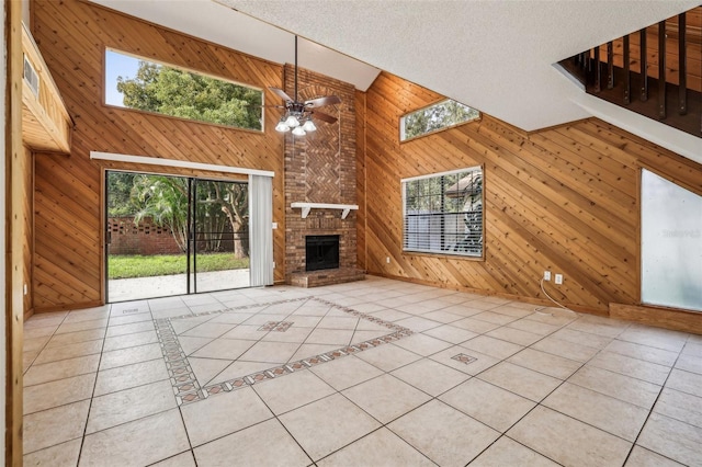 unfurnished living room with light tile patterned flooring, wooden walls, a textured ceiling, and a healthy amount of sunlight