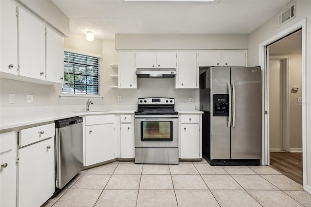 kitchen with appliances with stainless steel finishes, white cabinetry, sink, and light tile patterned floors