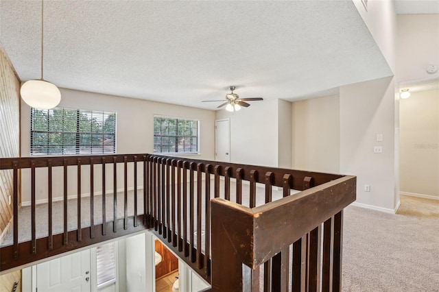 hall with light colored carpet and a textured ceiling