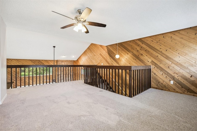 bonus room with ceiling fan, carpet floors, wood walls, and vaulted ceiling