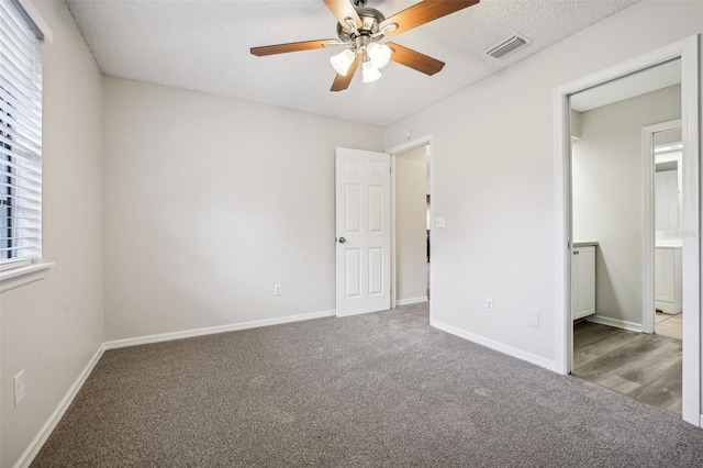 unfurnished bedroom with ceiling fan, carpet flooring, and a textured ceiling